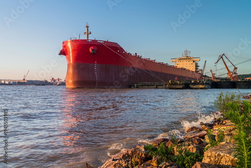 Stock images of Ship carrying containers with crude oil barrels from the harbour. Ship blocked in harbour.