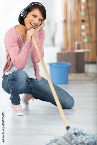 happy woman cleaning home singing at mop like at microphone
