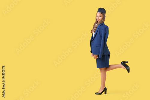 Cute teenage happy stewardess on yellow background