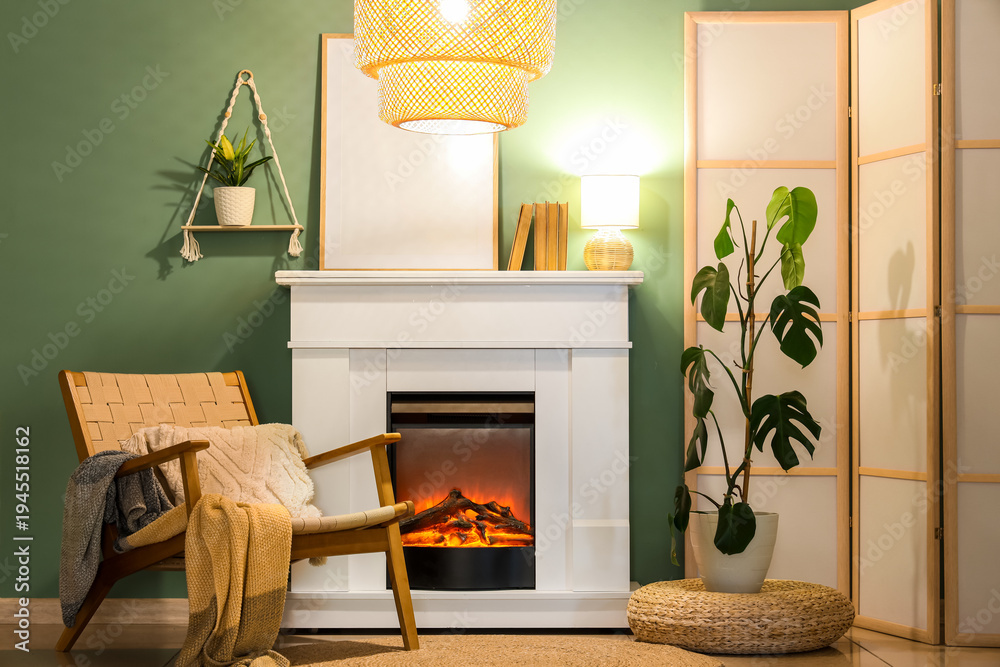 Naklejka premium Fireplace with armchair, glowing lamps and folding screen near turquoise wall in living room