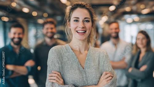 A confident woman smiles in front of her colleagues, showcasing teamwork and collaboration in a well-designed office space filled with natural light.
