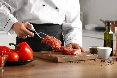 Male chef cutting raw meat ...