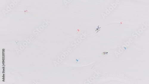 Top view drone shot of two skiers racing parallel slalom on snowy competition slope