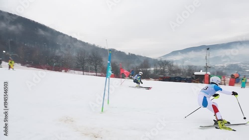 Two alpine skiers racing parallel slalom in slow motion passing slalom gate