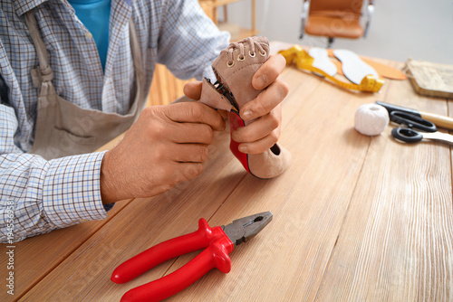 Mature shoemaker repairing ...