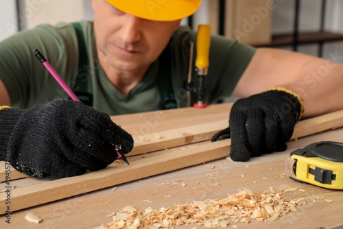 Male carpenter marking wood...