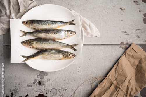 Fresh Raw Sardines on White Plate Over Rustic Stone Background, Top View
