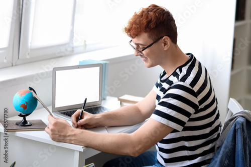Young redhead man writing i...