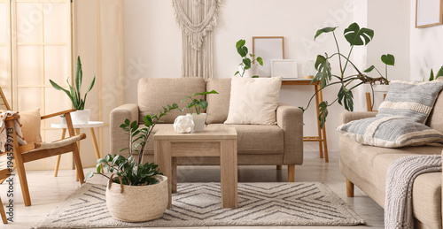 Interior of light living room with green plants, sofas and tables