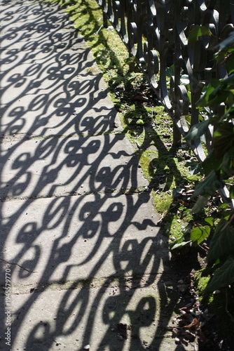 Decorative shadow pattern from metal fence on pavement