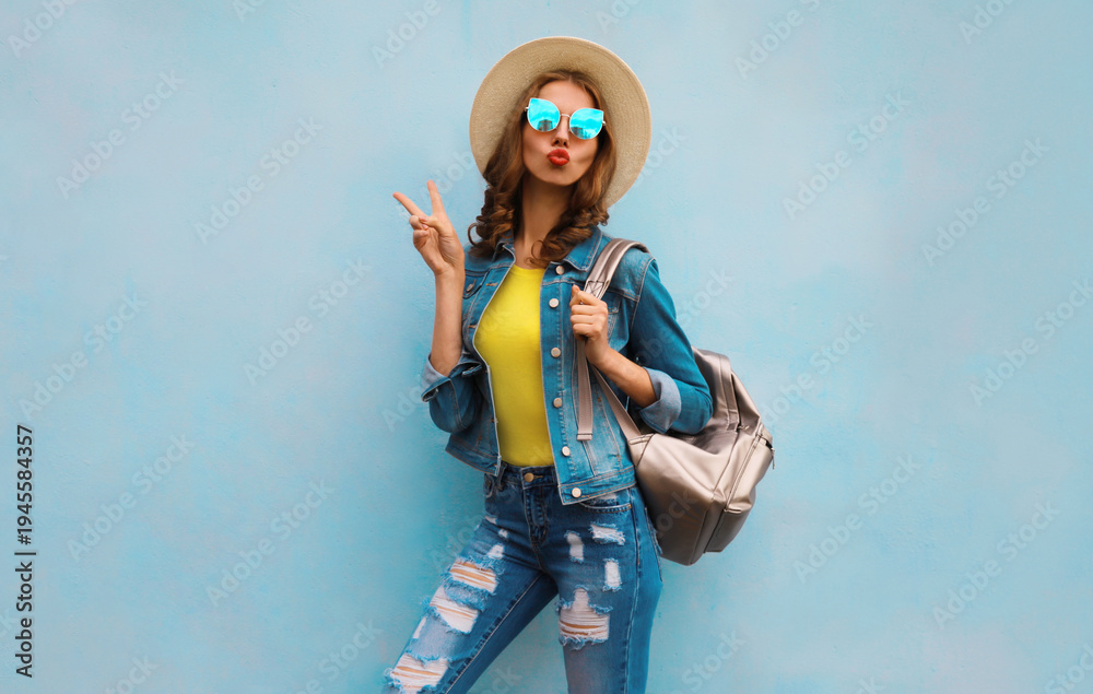 Obraz premium Stylish young woman in summer clothes with backpack posing on blue background