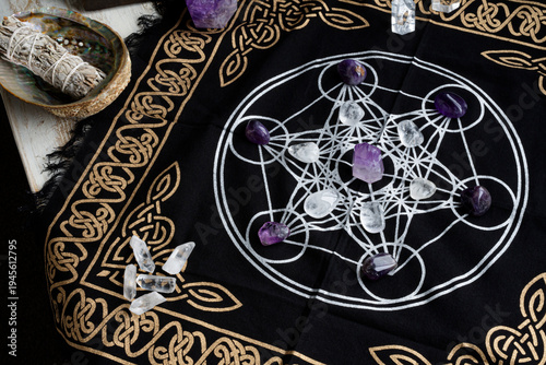 A top view image of a crystal healing grid using clear quartz and amethyst crystals along with white sage smudge stick and grid cloth. 