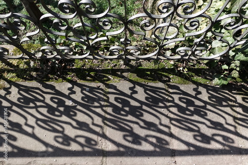 Abstract decorative shadow pattern from metal fence on pavement