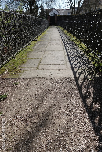 Perspective view along ornamental metal fence with shadow pattern
