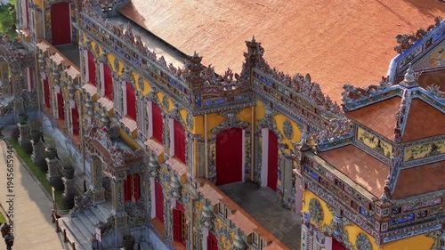 Kien Trung Palace in Hue Imperial City with a vibrant yellow facade, red shutters and roof details. Aerial Drone Shot