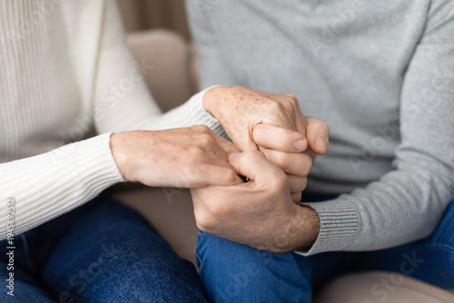 Closeup of senior couple holding hands in comforting gesture at home. Mature man and woman supporting each other during an emotional moment representing love, care, trust and long term relationship