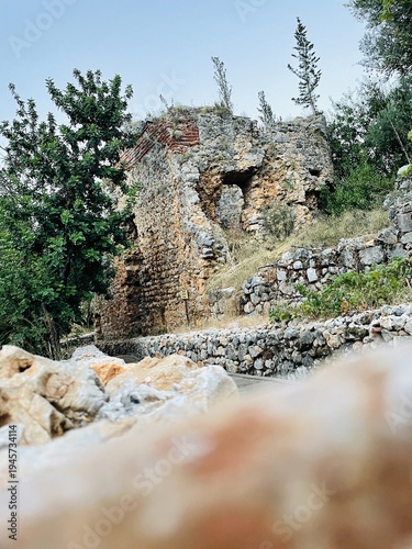 Old stone ruin viewed from low rocky foreground on pathway