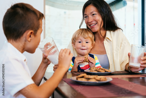 Bilde på lerret Asian family at home, asian mother and kids enjoying cookies and milk
