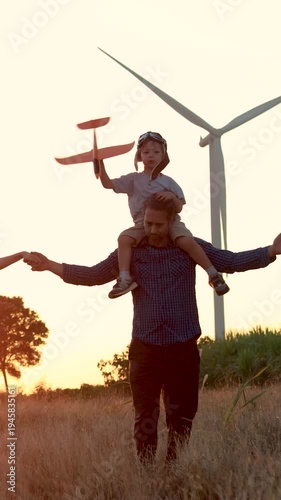 Family with son walking on field on wind farm. Happy Family and son playing at the Wind turbines generating electricity. Family time together.