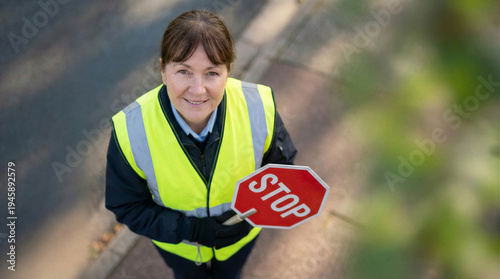 Wallpaper Mural A friendly female crossing guard in a bright yellow reflective vest holds a stop sign, smiling upwards at the camera. Torontodigital.ca
