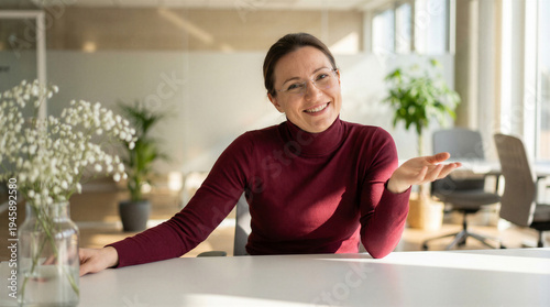 Wallpaper Mural A friendly smiling businesswoman sits at a white desk in a bright, modern office, gesturing invitingly with an open hand. Torontodigital.ca