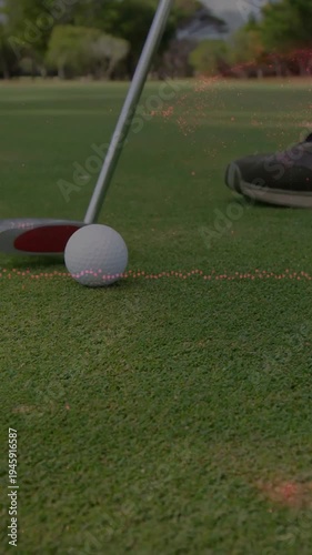Vertical video: Golfer swinging putter causing overlay guiding golf ball into cup, aiming for hole
