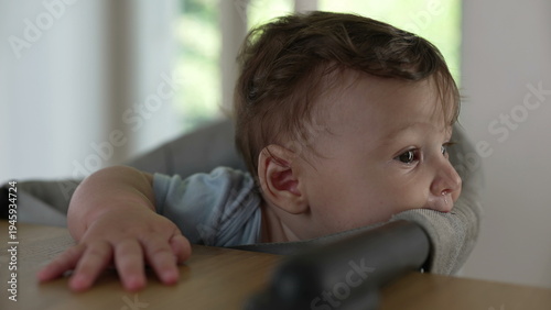 Fotografija Baby biting high chair fabric, exploring texture with mouth, early teething beha