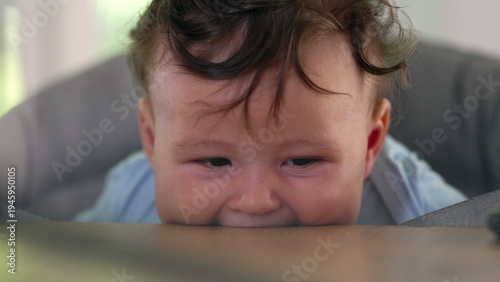 Quadro em tela Baby lying on dining table, biting surface, big-eyed expression, early childhood