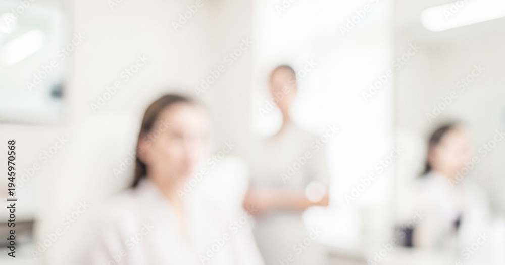 Fototapeta premium A soft-focused image depicting two women in a spa setting. One woman is seated, while another stands in the background, creating a serene atmosphere.