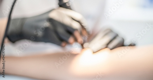 A close-up view of a tattoo artist's hands wearing gloves while working on a tattoo on a client's arm in a professional studio.
