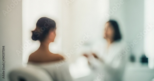 A blurred image featuring a woman receiving consultation or treatment at a beauty or wellness clinic, highlighting relaxation and care in a serene environment.