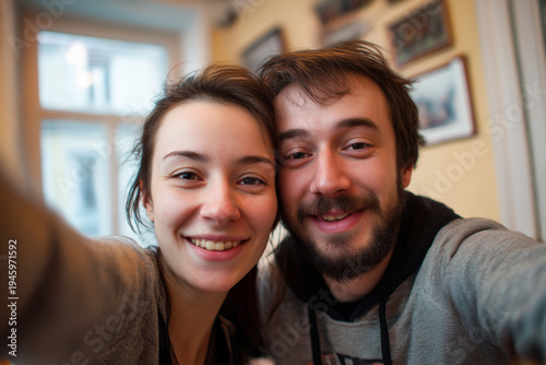 Cheerful young couple making funny faces while taking a wide-angle selfie on city street