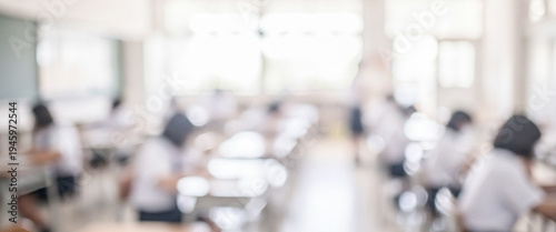 A blurred interior of a classroom filled with students engaged in learning activities. The soft focus creates a serene educational atmosphere.