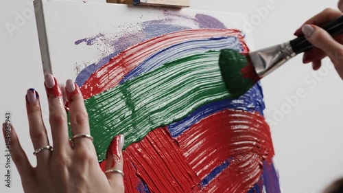 Wallpaper Mural Woman's hands hold canvas while another person paints with red and blue brushstrokes in studio background Torontodigital.ca
