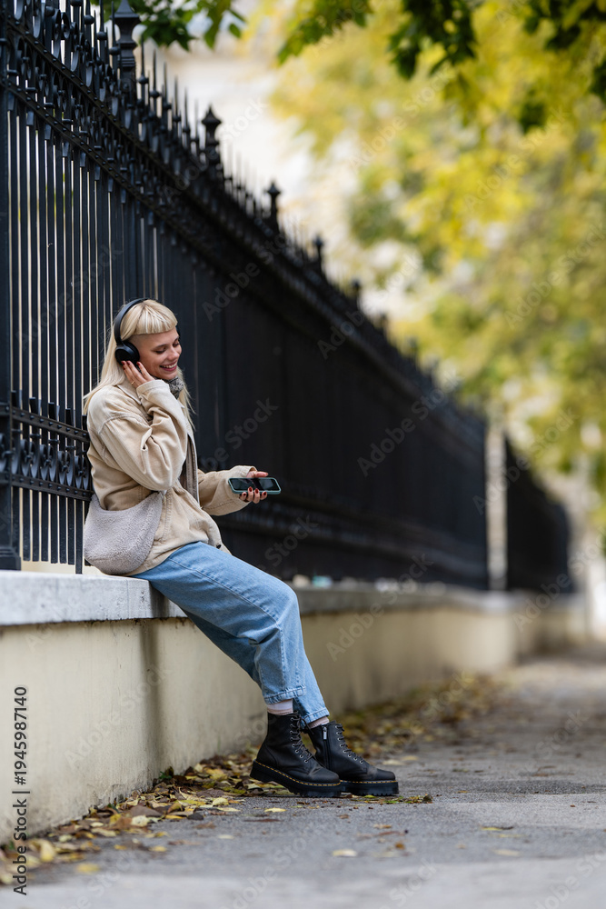Fototapeta premium Young woman enjoying music on phone outside