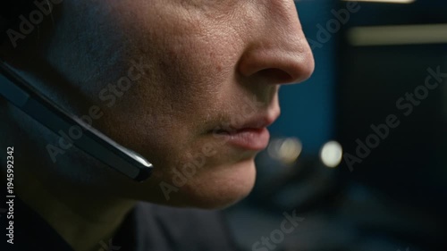 Side view close up shot of adult female dispatcher at police station and speaking to headset controlling operations with focus on lips moving, copy space