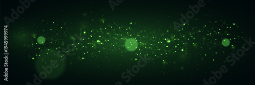 Glowing green magic particles and sparkling light dust on dark background.