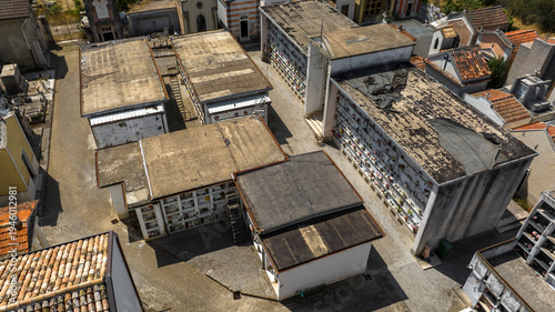 Aerial view of a Italian cemetery featuring rows of tombs and loculi. The architectural layout reflects solemn traditions, combining modern and historical burial structures in a quiet city of the dead