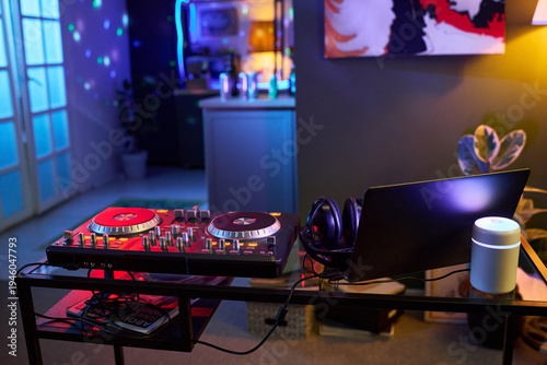 Φωτογραφία DJ controller with headphones and laptop standing on table in room, colorful lig