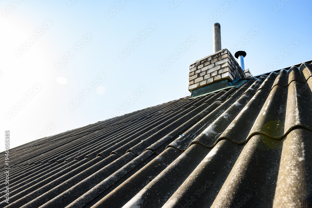 Fototapeta premium Chimney pipe from stainless steel on the roof of the house. Repair of roof chimney, brickwork.