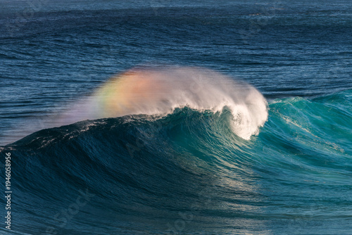 Powerful ocean wave breaking with sea spray and white water under clear blue sky along the coast of Sydney, Australia.