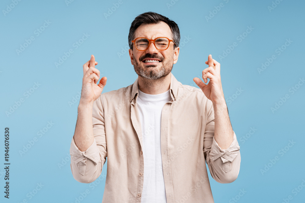 Naklejka premium Man crossing fingers, eyes closed, wishing for good luck and success