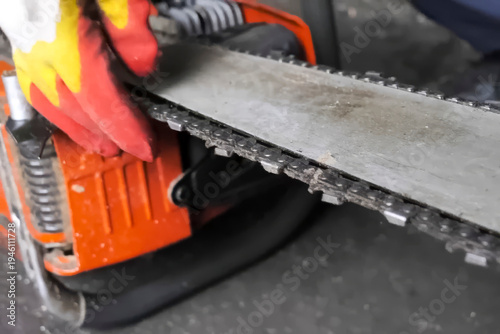 worker adjusts the chain on the chainsaw bar.