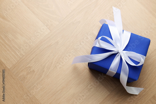 Beautiful gift box with bow on wooden table, top view. Space for text