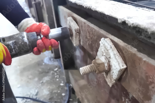 Worker unscrewing nuts with pneumatic wrench