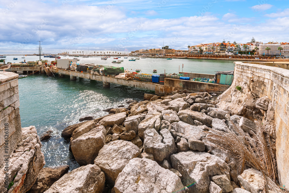 Fototapeta premium The rocky coastline along the scenic bay and marina of Cascais, Portugal, a historic fishing town turned popular seaside resort along the Portuguese Riviera.