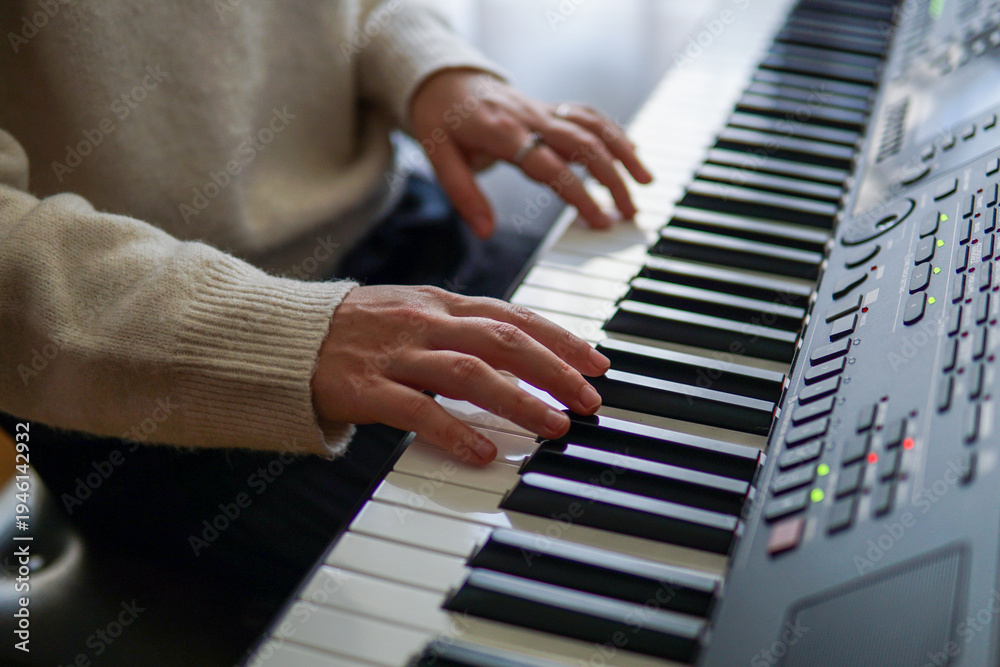 Fototapeta premium Woman playing piano, close up of hands on piano keys, music practice and creativity