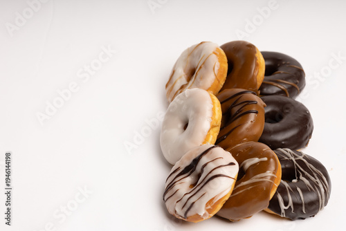 Assorted glazed donuts with different toppings stacked on a white background
