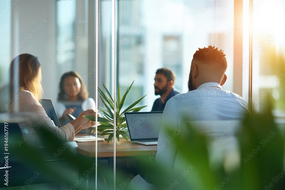 Fototapeta premium Business professionals collaborating and discussing during a meeting in a bright, modern office with laptops and natural light