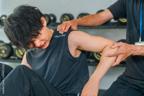 Φωτογραφία A man experiencing shoulder pain during training and a male sports physical therapist